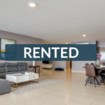 Modern living and dining room with a gray sectional and wooden table, overlaid with a Panama Equity RENTED banner.