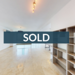 Bright empty room with polished tile floors and a built-in wood bookshelf, overlaid with a SOLD banner.