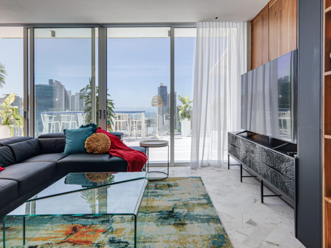 Image of the living area with a couch, table, and windows looking out onto the city skyline at wanders & yoo