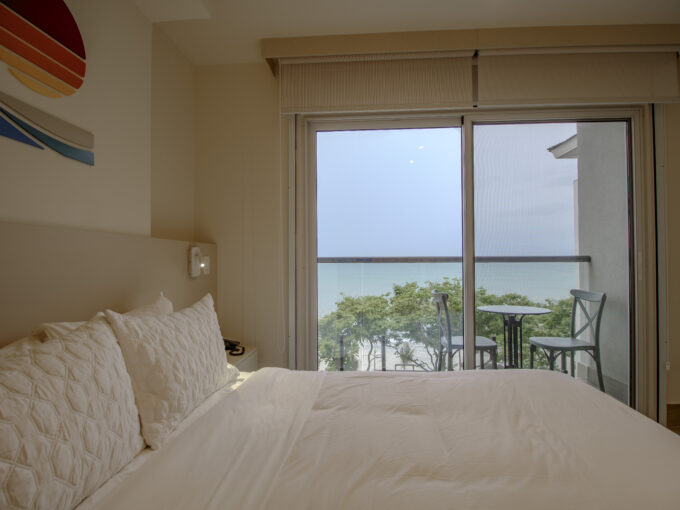 Image of bedroom with floor to ceiling window and bed in this condo in surfside, playa caracol