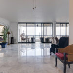 Image of the living area with a chair, plant, and balcony in this condo in Torre La Cresta