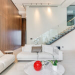 Image of living area with couch, table and stairwell in this condo in Oasis on the Bay