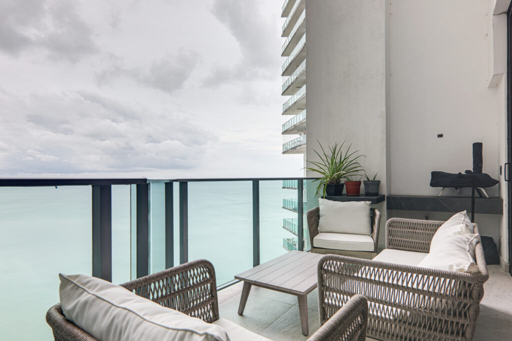 Image of balcony with two chairs and table and ocean views in this condo in Oasis on the Bay