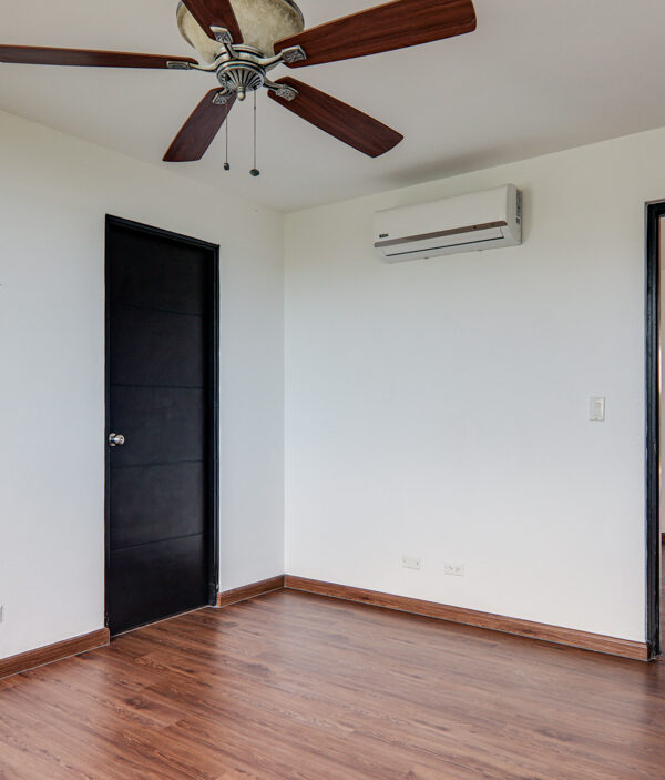 Image of bedroom with fan and door in this penthouse in Pine Hill