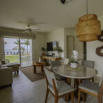 Image of living dining area with couch, table, chairs and view of the beach in this Beachfront Villa for Sale in The Residences, Playa Caracol