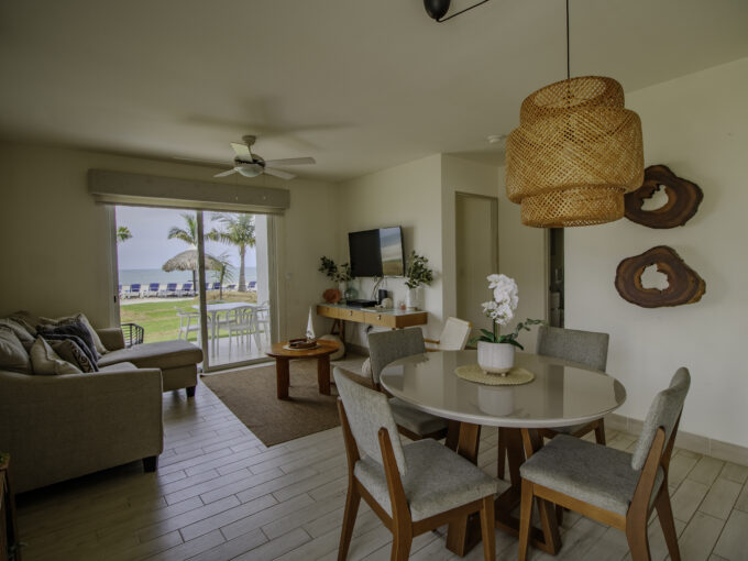 Image of living dining area with couch, table, chairs and view of the beach in this Beachfront Villa for Sale in The Residences, Playa Caracol