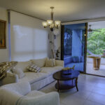 Image of living area with couch and table leading onto balcony in this condo for sale in Galeones, Ensenada