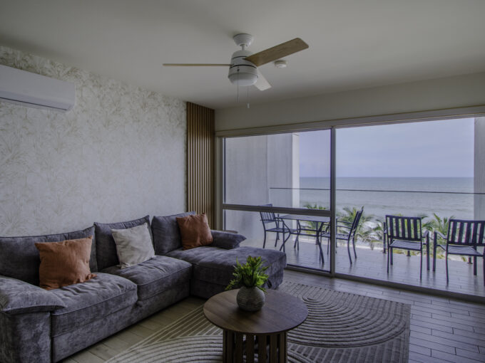 Image of living area with table, couch and window with view of the ocean and beach in this condo for sale in Solares, Sanctuary in Playa Caracol
