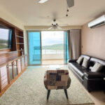 Image of living room with couch, chair and balcony looking out onto the water in this condo for sale in Casa Bonita