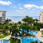 Large swimming pool surrounded by palm trees and facing the water in Ventanas del Mar