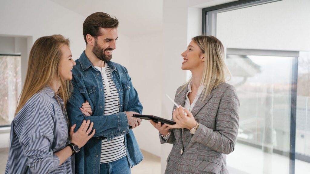 Real estate agent presenting property details on a tablet to a smiling young couple pursuing permanent residency in Panama real estate services in Panamá by Panama Equity Real Estate