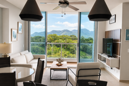 Large living room with furniture and balcony showing green views in this condo in Royal Palm