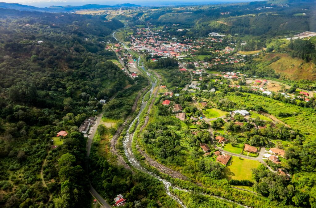 Aerial view of a lush green mountain valley and river running through a town during the best time to visit Panama real estate services in Boquete by Panama Equity Real Estate