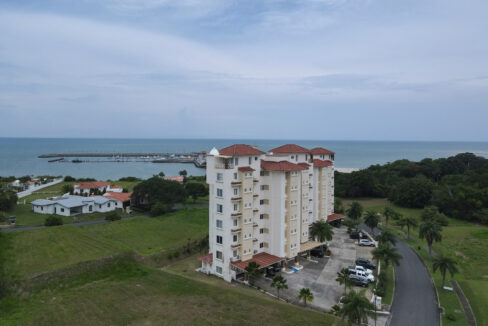 The Rocamarina building in Vista Mar seen from the air, with lawns, palms and the ocean behind it.